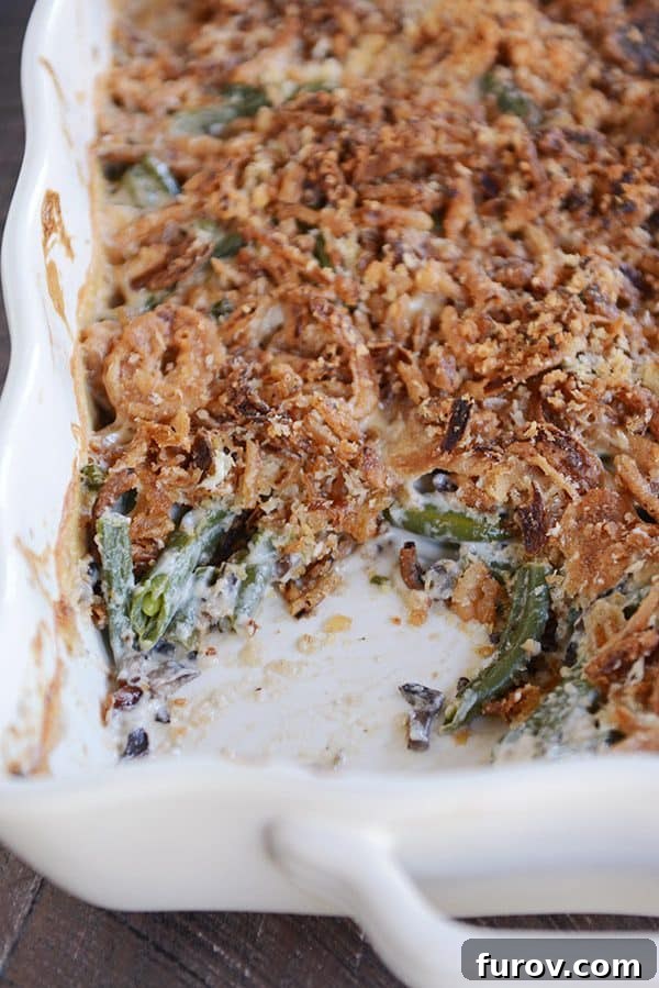 Top view of a white casserole dish full of green bean casserole topped with crunchy topping, ready for the oven.