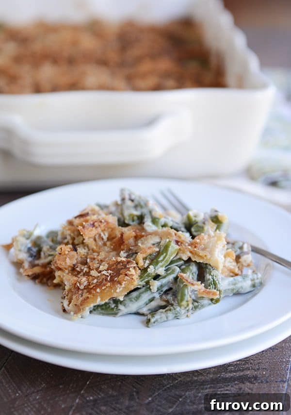 Green bean casserole with crunchy topping on a white plate, garnished and ready to eat.
