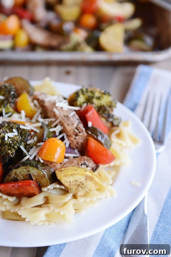 Easy One Pan Balsamic Chicken and Vegetables in 30 Minutes 3 A close-up shot of pasta topped with strips of balsamic chicken and a colorful medley of roasted vegetables.