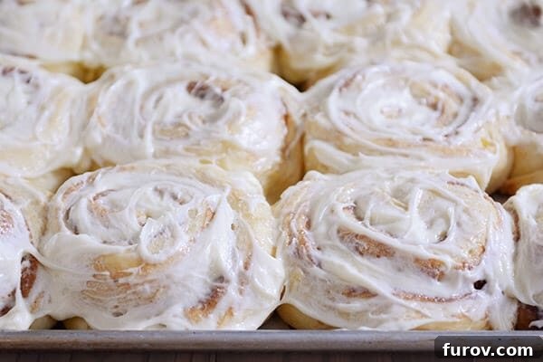 A close-up view of a pan brimming with freshly frosted cinnamon rolls, inviting you to take a bite.