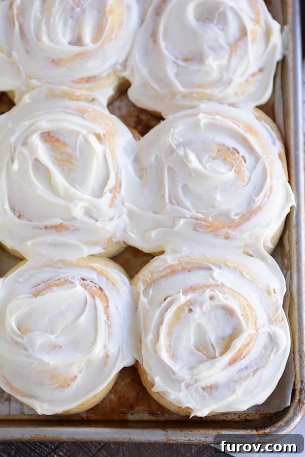 Top view of a pan of generously frosted cinnamon rolls, glistening and ready to be served.