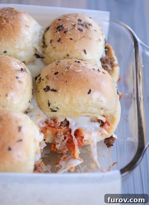 A glass baking dish filled with hot, bubbling cheesy pepperoni pizza sliders.