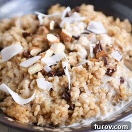 Coconut milk steel cut oats in brown bowl with chocolate chips, almonds and coconut.
