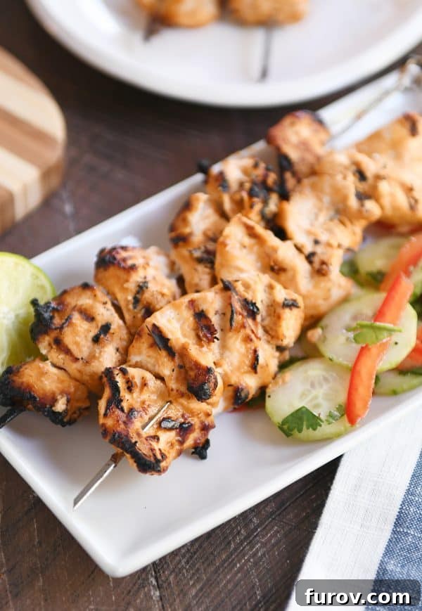 Cucumber salad with vibrant almond coconut milk chicken satay on a pristine white platter, showcasing a perfect summer meal.