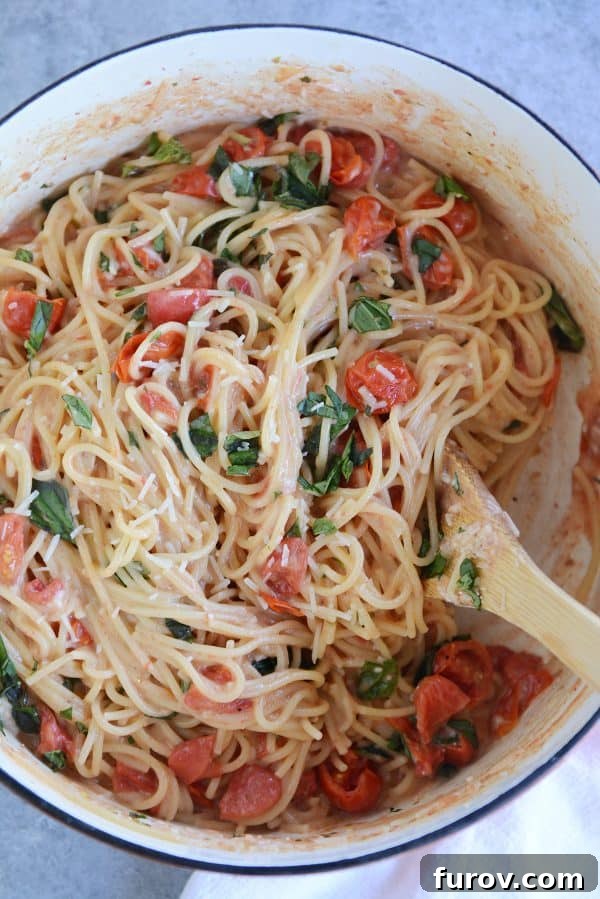 One pot creamy tomato basil pasta in ceramic pot, garnished with fresh basil.