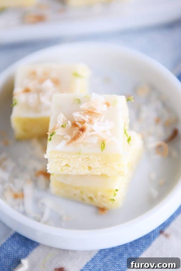 Stacked toasted coconut lime bars on a white circular plate, highlighting the delightful combination of textures.