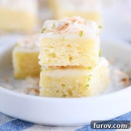 Toasted coconut lime bars stacked on white circle plate, perfect for a refreshing dessert.