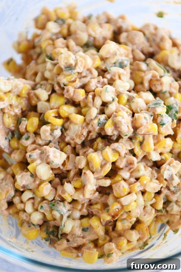 Zesty Mexican Street Corn Salad 5 A vibrant top-down view of Mexican street corn salad in a clear glass bowl, showcasing its colorful ingredients and creamy texture.