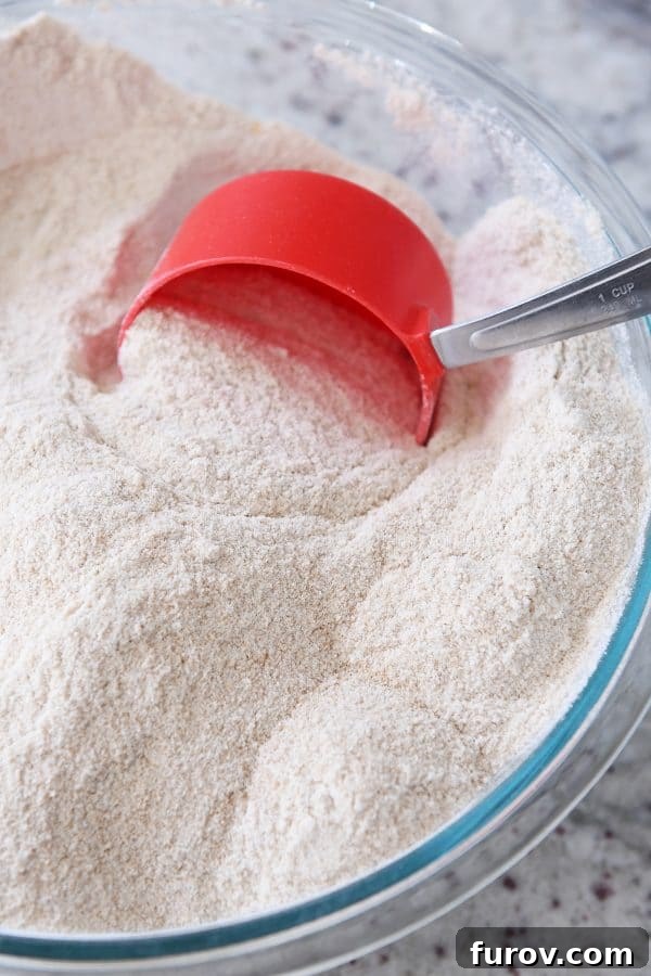 Scooping whole wheat flour out of bowl.