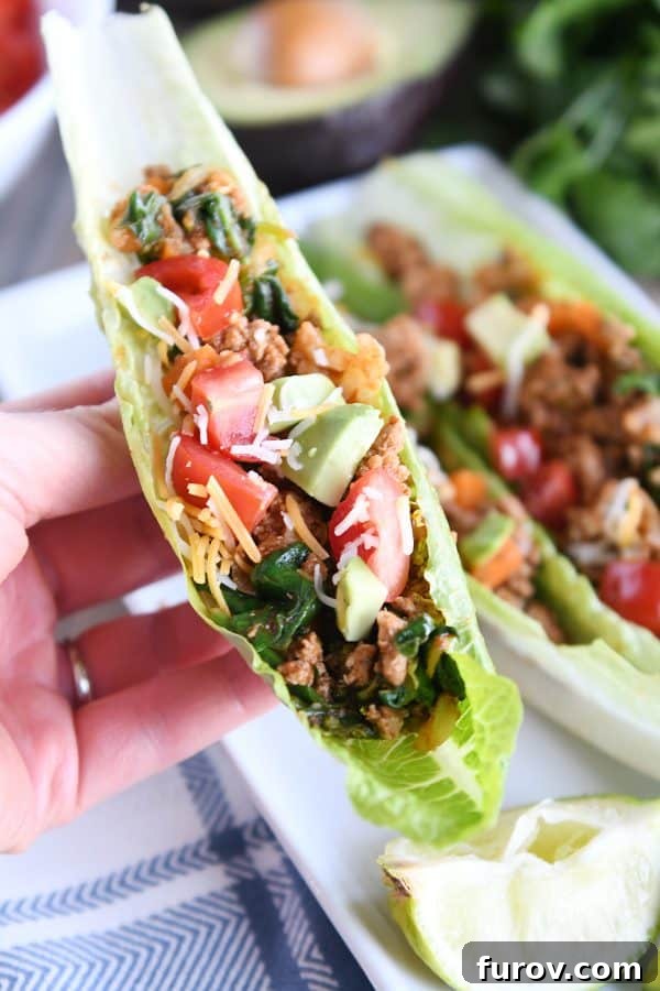 Vibrant Veggie Turkey Lettuce Tacos 4 A hand holding a single veggie turkey taco lettuce cup, showcasing the vibrant filling and fresh toppings.
