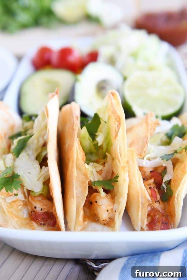 Golden Crunch Shrimp Tacos 2 Three perfectly crispy baked shrimp tacos, garnished with fresh shredded lettuce, arranged neatly on a pristine white serving tray.