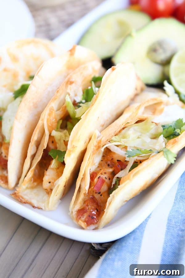 Golden Crunch Shrimp Tacos 4 A trio of crispy, golden shrimp tacos, beautifully presented with fresh lettuce, on a clean white serving tray, ready to be devoured.