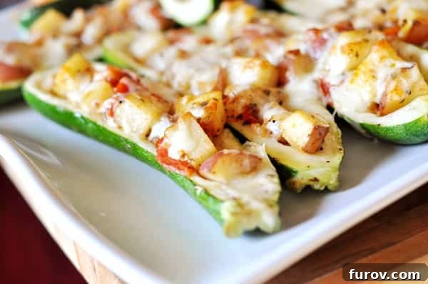 Beautifully baked stuffed zucchini on a pristine white platter, showcasing the golden-brown cheese topping and vibrant filling.