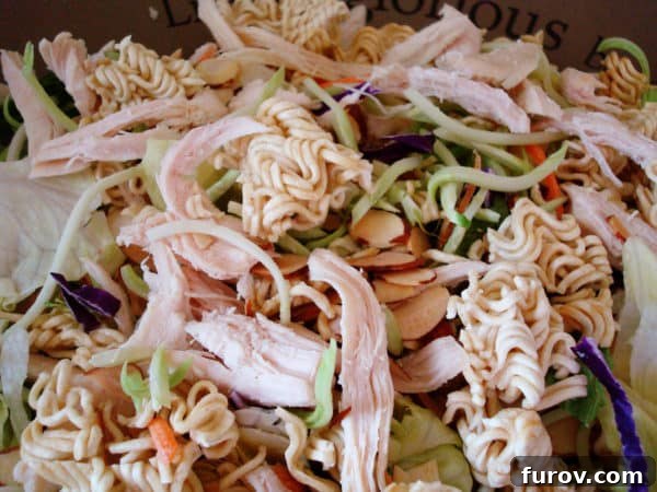 A large bowl filled with Asian salad ingredients, showing the mix of greens, chicken, and other fresh components before dressing.