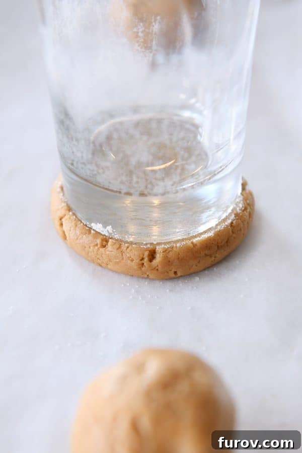 Pressing ball of gingerbread sugar cookie dough with glass coated in sugar.