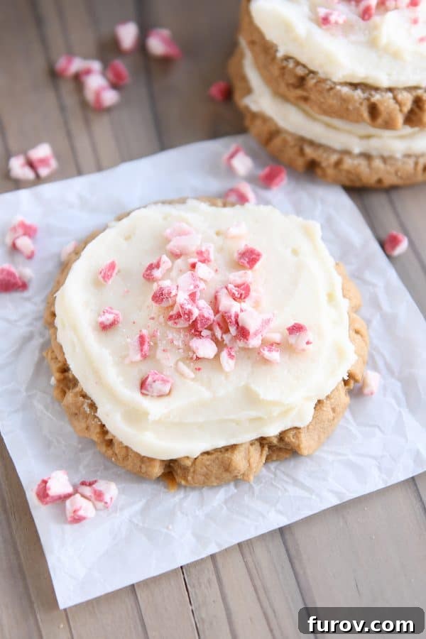 Frosted gingerbread sugar cookie on white parchment paper with peppermint crunch candies.