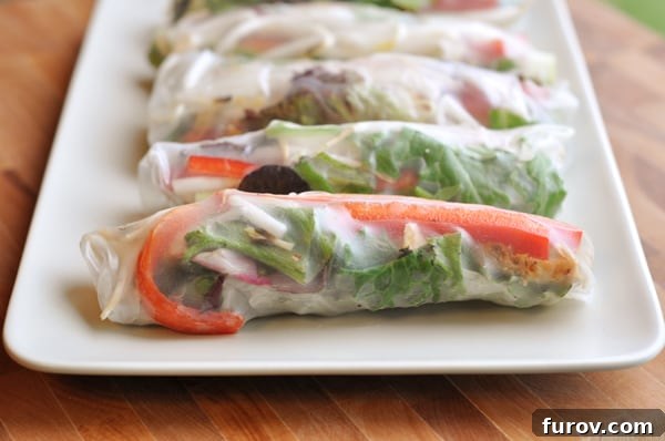 Freshly rolled Vietnamese spring rolls neatly arranged on a white platter.