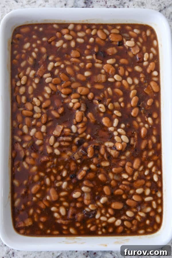 An unbaked pan of white beans and sauce, ready for the oven to transform them into saucy baked beans.