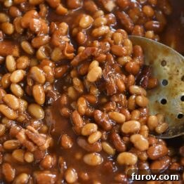 slotted spoon in dish of saucy baked beans