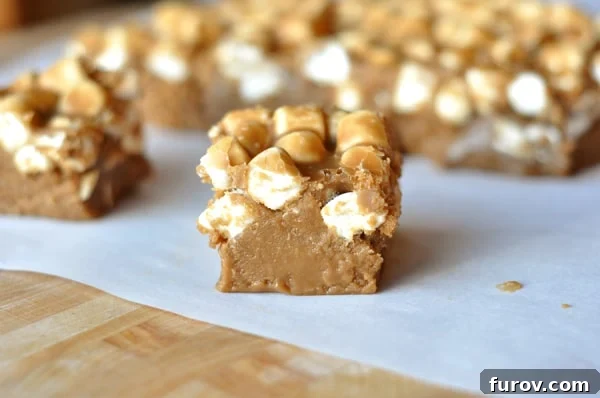 Light-colored squares of Root Beer Float Fudge, topped with mini marshmallows, arranged on a piece of parchment paper.
