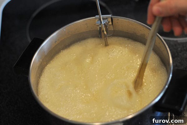 Boiling butter and sugar mixture being stirred by a wooden spoon, showing significant bubbling and foaming.