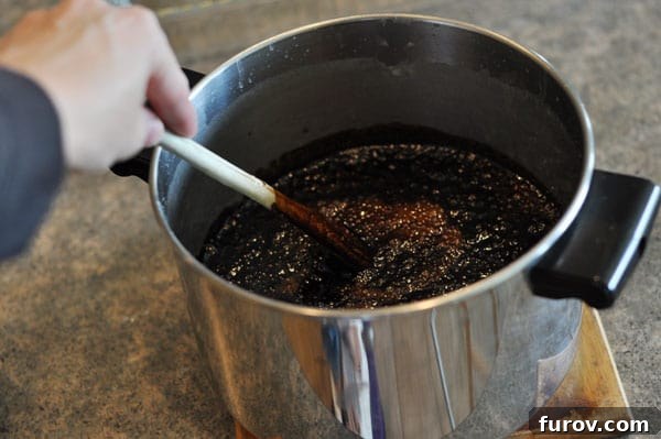 A wooden spoon stirring a bubbling fudge mixture after the extracts have been added.