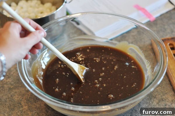 Bubbly, lightened fudge mixture in a glass bowl, perfectly prepared to receive marshmallows.