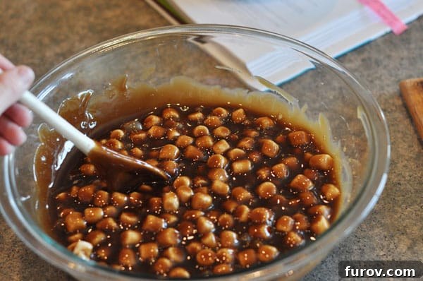Dark colored fudge with marshmallows mixed in, evenly distributed throughout the mixture in a glass bowl.