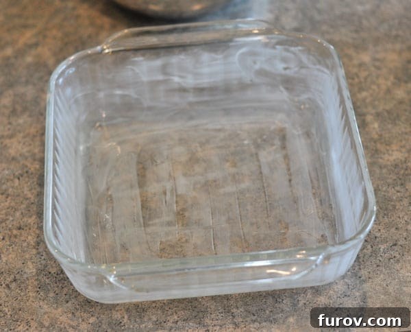 A perfectly buttered 8x8 inch baking pan, ready to receive the fudge mixture.