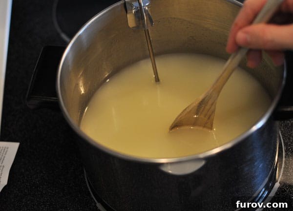 Melted sugar mixture in a pot being stirred with a wooden spoon, showing a smooth, combined consistency.