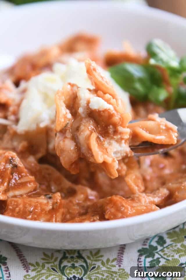 Scooping a bite of one-pot chicken lasagna onto a fork, showing the creamy, cheesy texture.