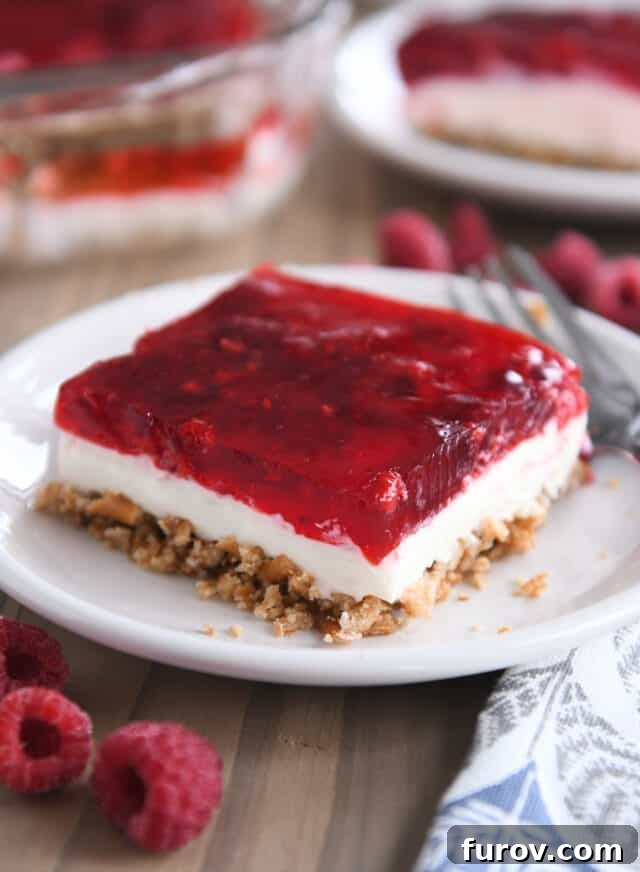 A beautifully cut square of Raspberry Pretzel Jello presented on a simple white plate, ready to be enjoyed.