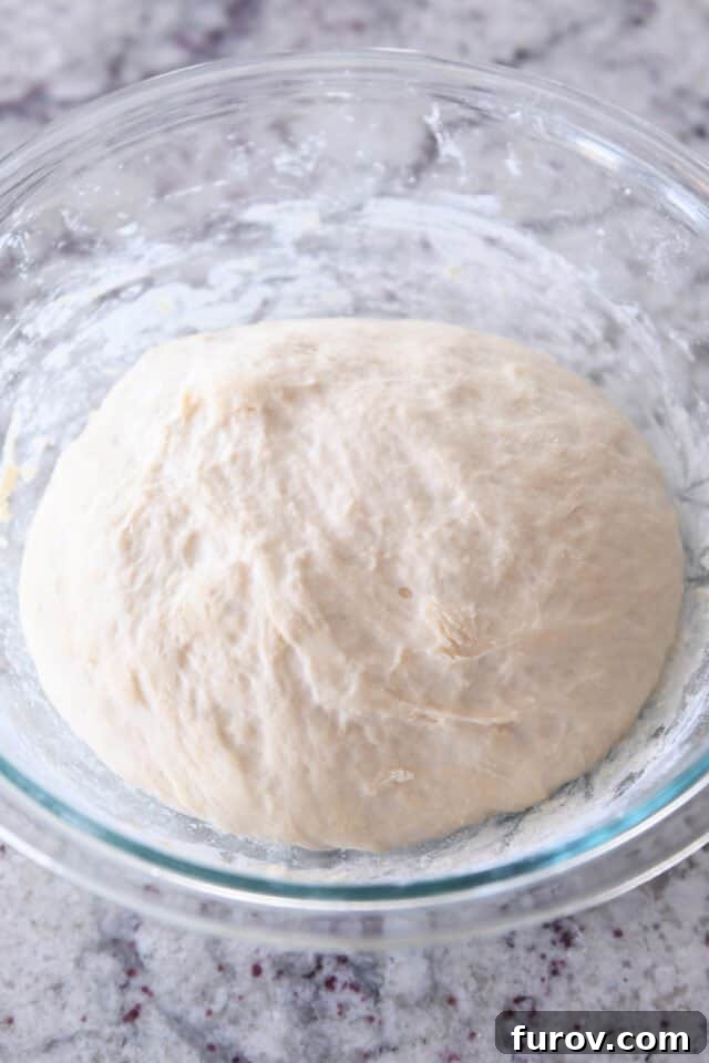 Risen breadstick dough in glass bowl, ready for the next step.
