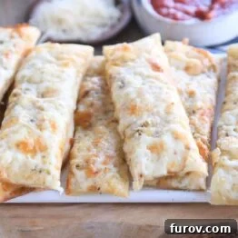 eight cheesy breadsticks on wood cutting board, showcasing the final product.