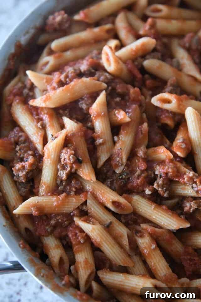 Make Ahead Freezer Friendly Cheesy Weeknight Pasta Bake 4 Penne noodles in pan with red sauce and ground beef.