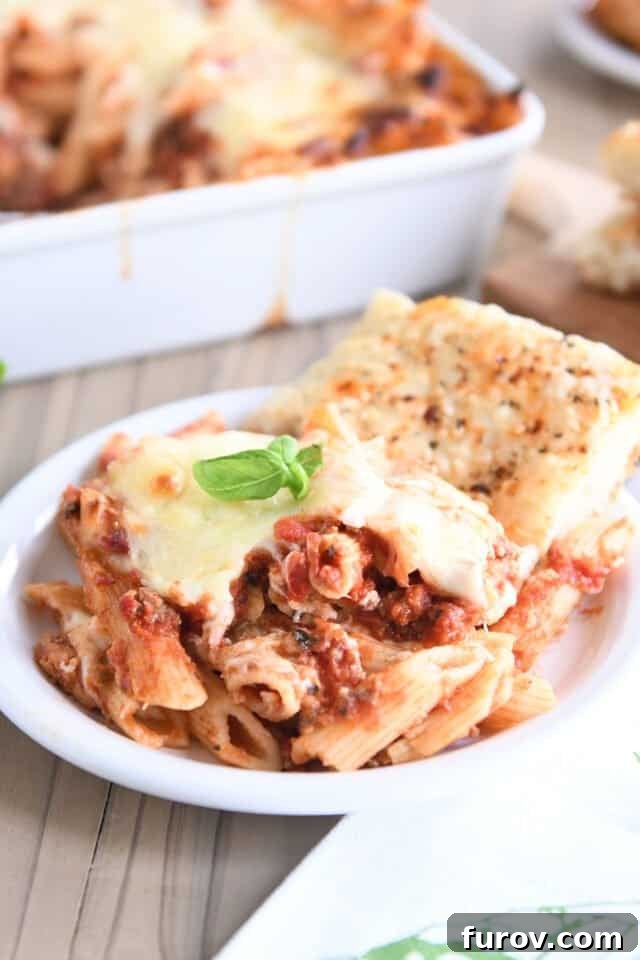 Make Ahead Freezer Friendly Cheesy Weeknight Pasta Bake 6 Serving of cheesy pasta bake on white plate with focaccia bread.