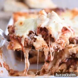 scooping serving of easy cheesy weeknight pasta bake out of white 9X13-inch pan