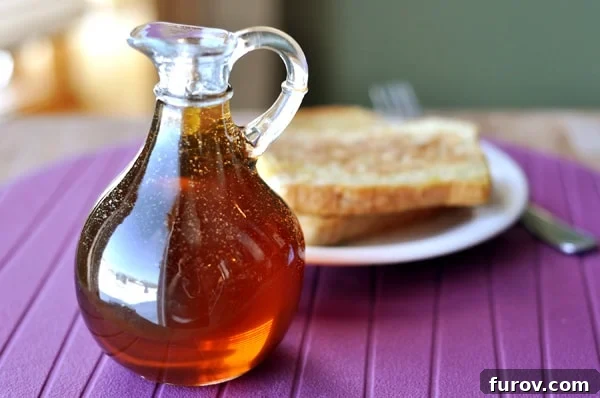 A jug of homemade maple syrup in front of a plate of french toast, symbolizing a delicious breakfast solution.