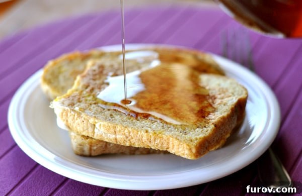 A plate of french toast with homemade maple syrup being generously drizzled over it.