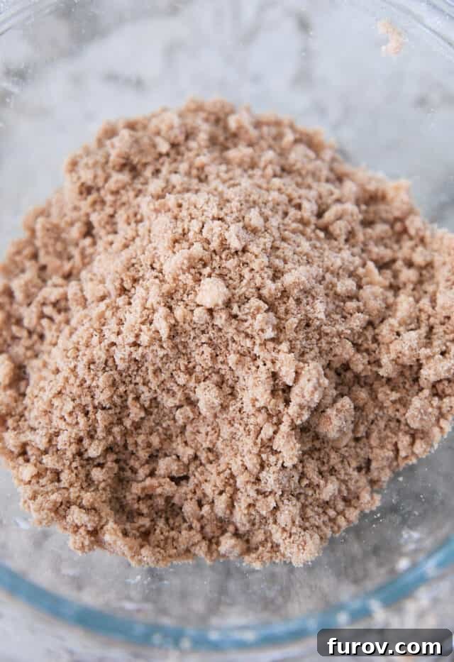 A glass bowl filled with perfectly crumbly cinnamon streusel topping, glistening and ready to adorn the pumpkin muffins.