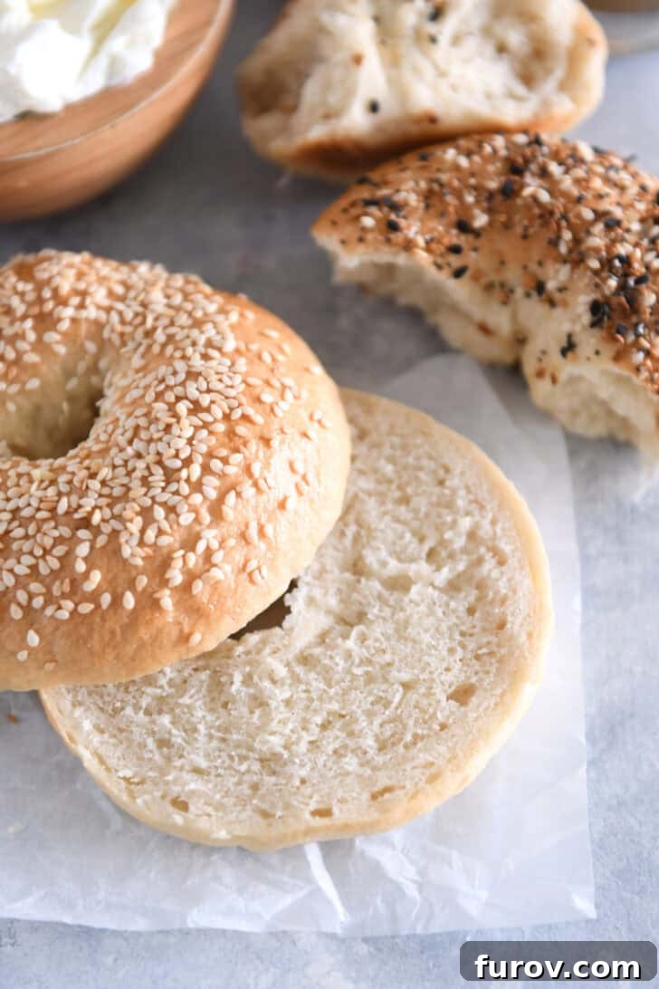 A perfectly baked homemade bagel, topped with sesame seeds and cut in half, revealing its chewy interior.