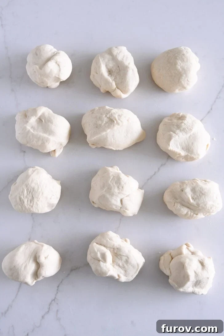 Dough split into 12 pieces on white counter, ready for shaping.