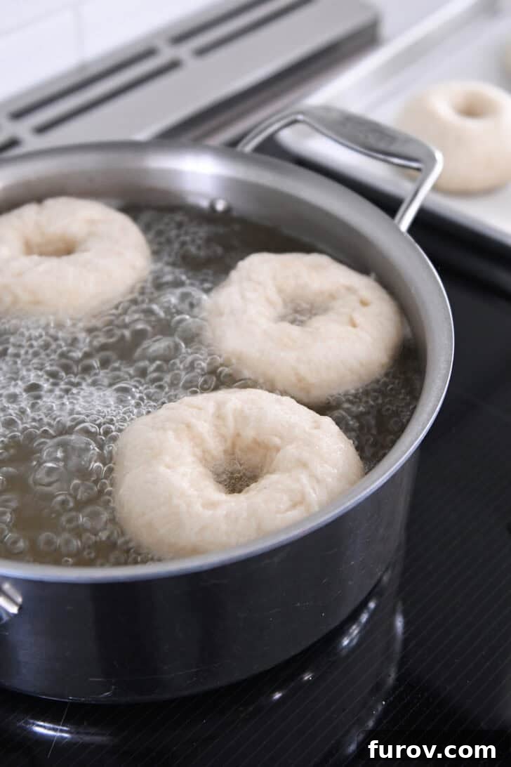 Bagels boiling in a simmering water bath with honey, creating their signature texture.