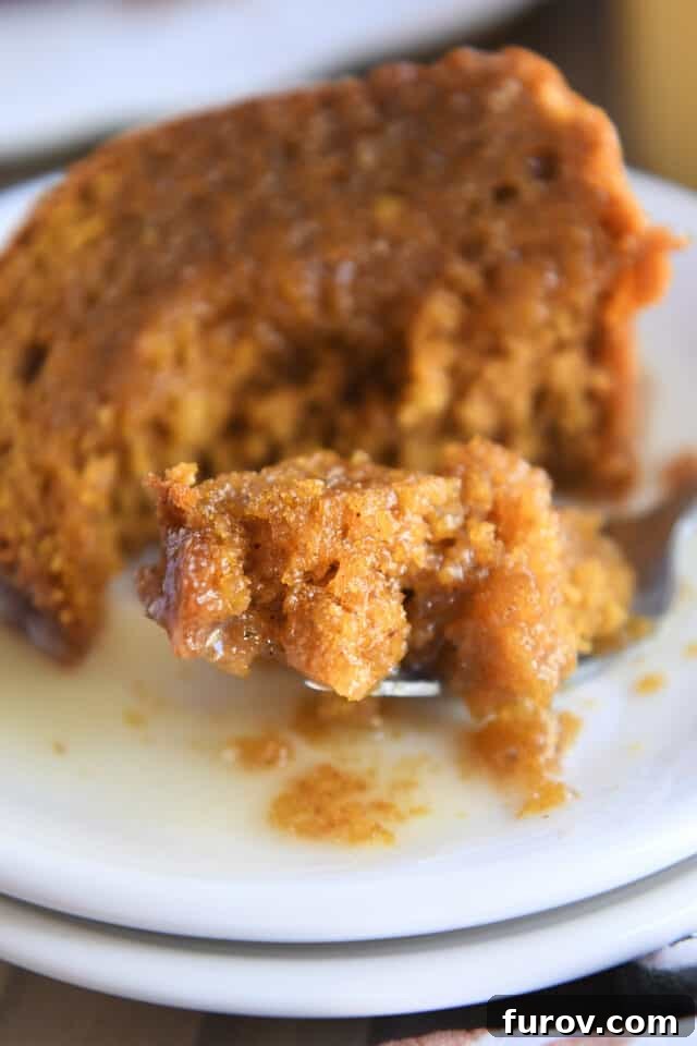 Bite of sauce-drenched cake on fork on white plate, showcasing the delicious pairing.