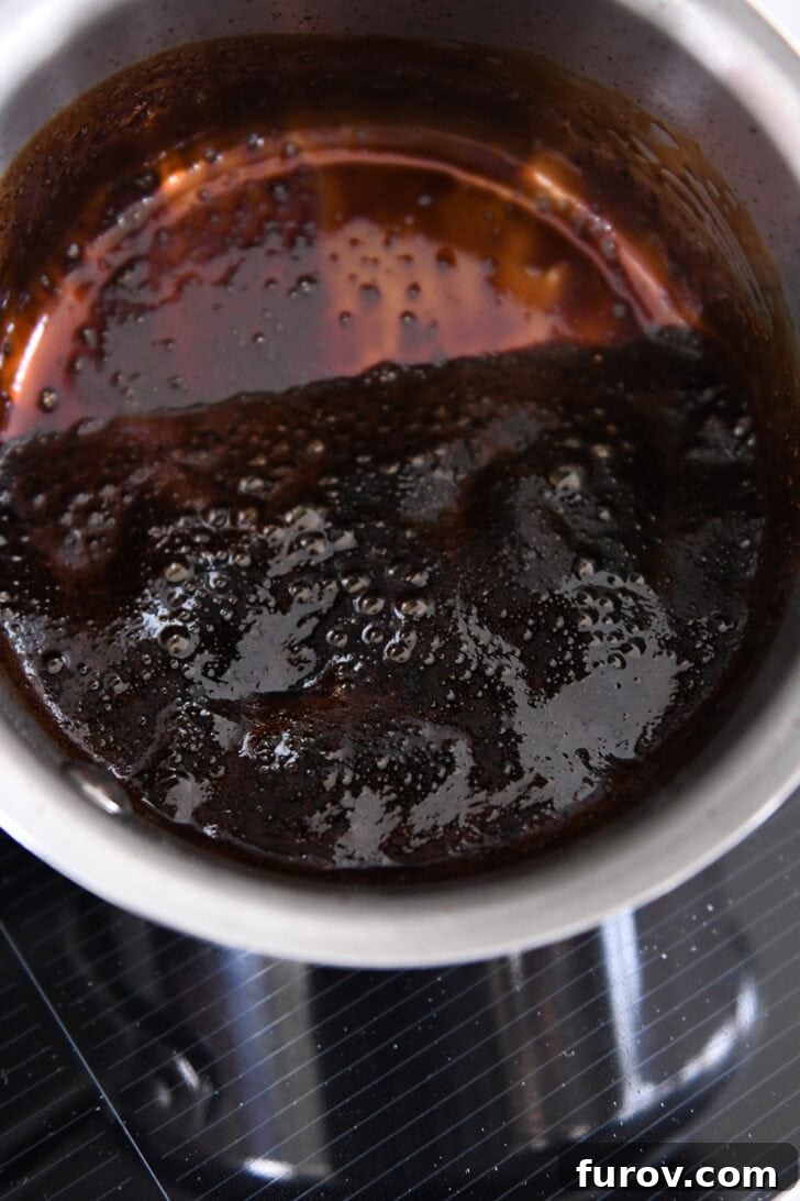 Thick reduced balsamic vinegar simmering in a small stainless pot.