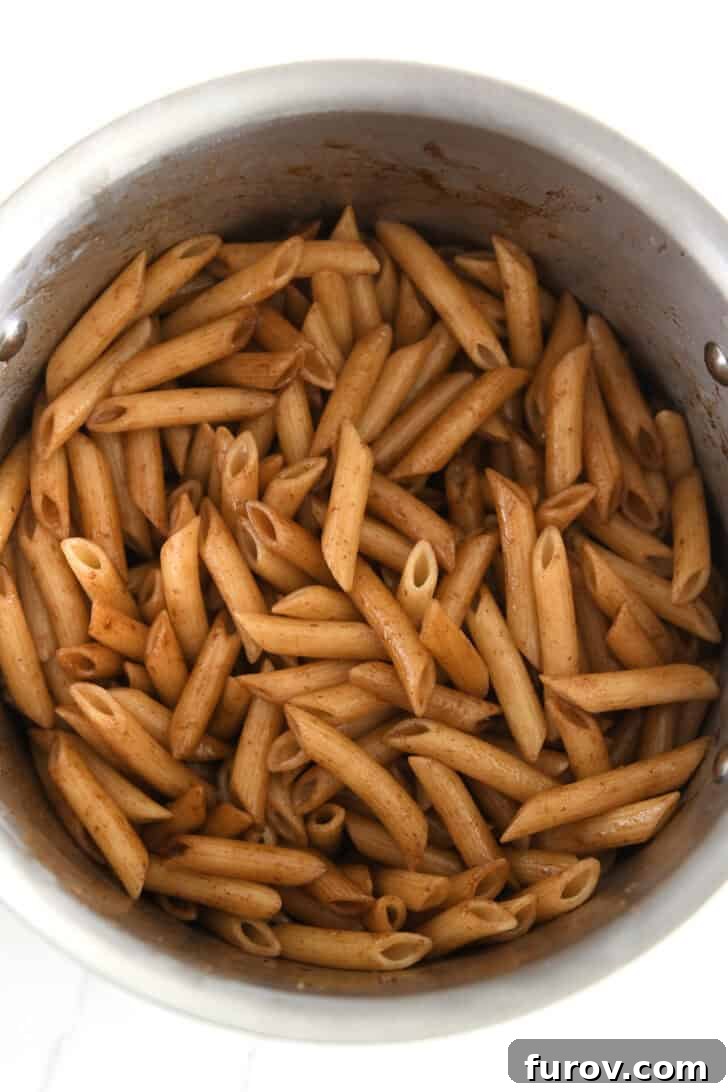 Stainless pot filled with perfectly cooked penne pasta and balsamic butter sauce.