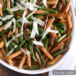 White serving dish with balsamic penne pasta, parmesan cheese and roasted asparagus.