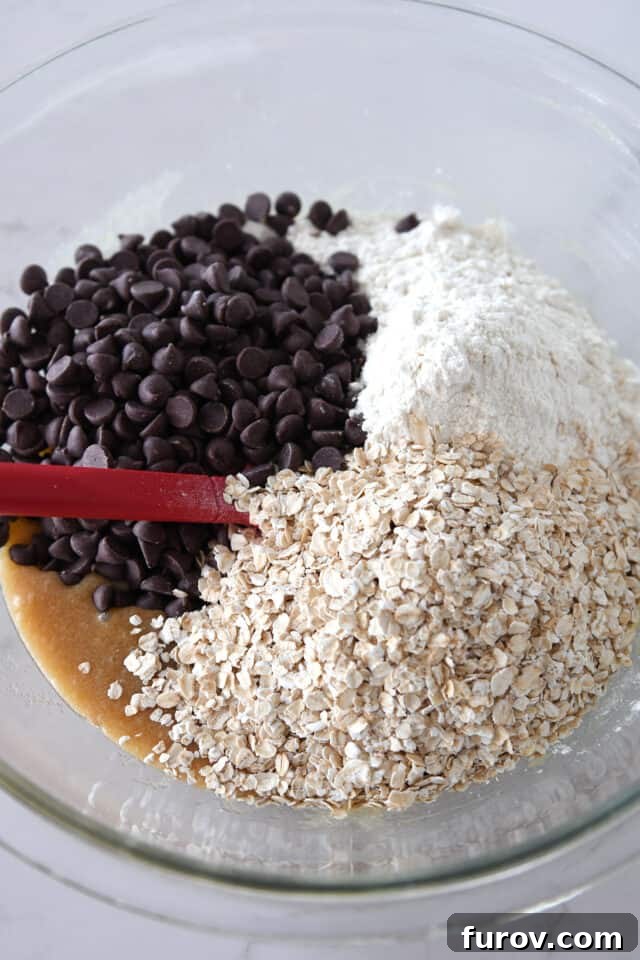 Homestyle Oatmeal Chocolate Chip Cookie Bars 4 Glass bowl filled with chocolate chips, flour, and oatmeal, preparing for the dry ingredients to be mixed.