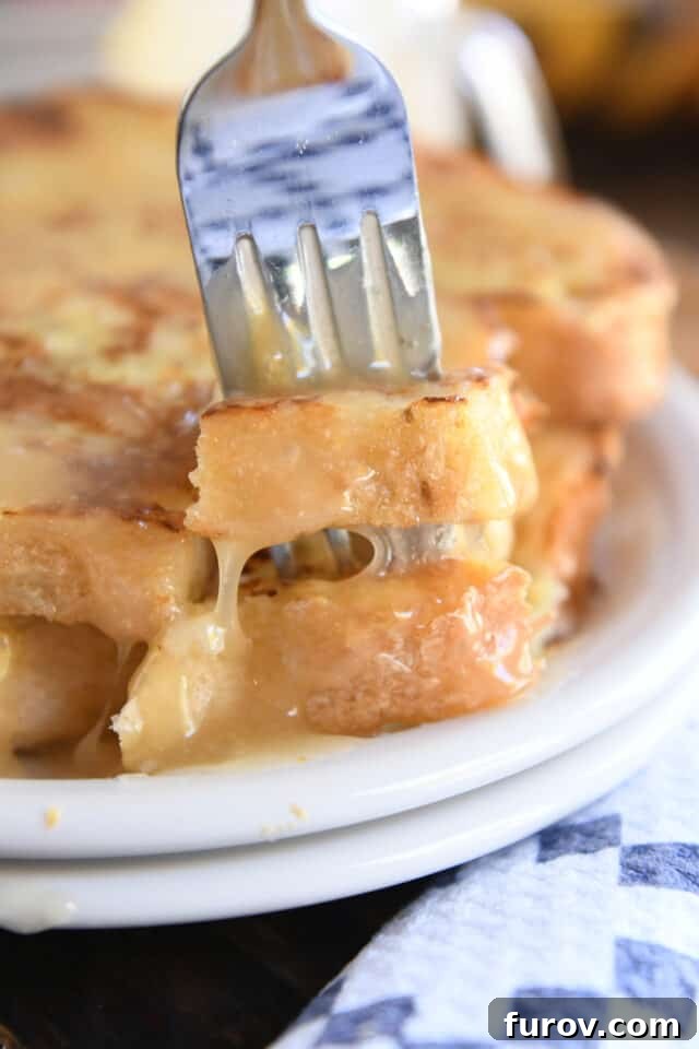 Velvety Buttermilk Caramel 9 Fork piercing two pieces of French toast on white plate.