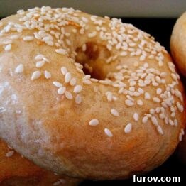 A stack of golden-brown homemade bagels with a variety of toppings like sesame and poppy seeds, ready to be enjoyed.